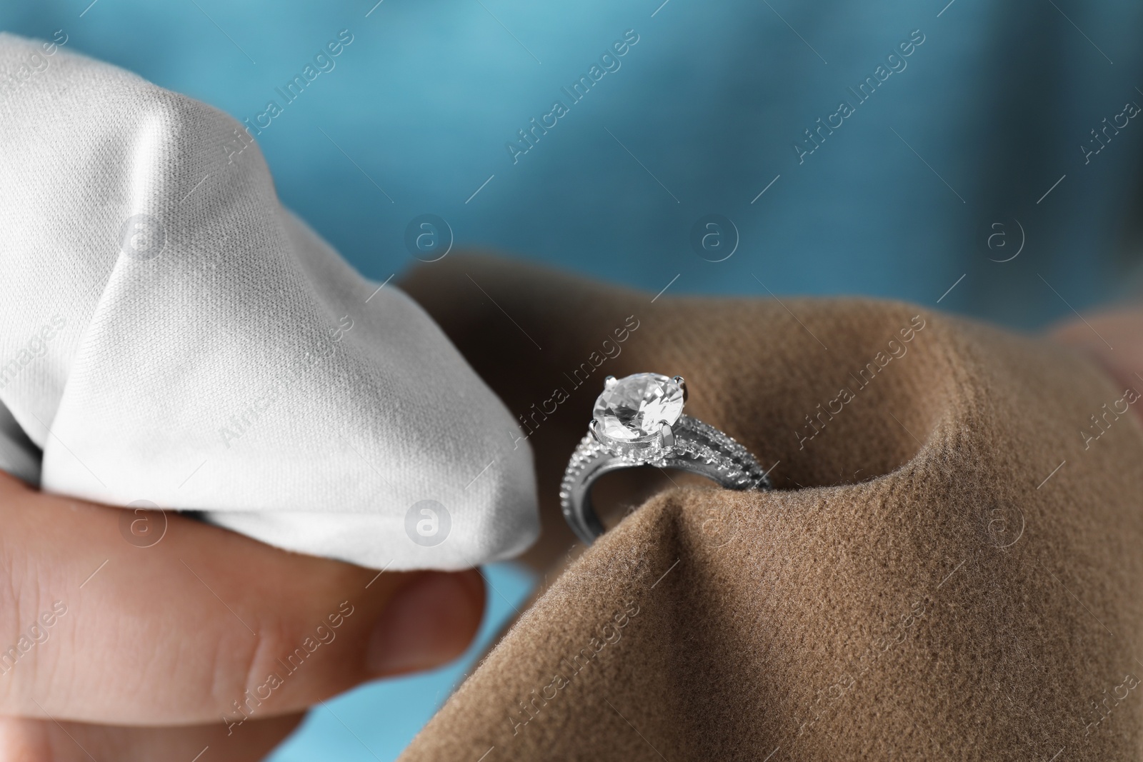 Photo of Jeweler cleaning diamond ring with microfiber cloth, closeup