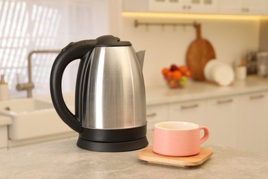 Photo of Electric kettle and cup on table in kitchen