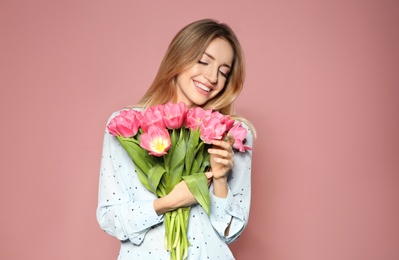 Photo of Portrait of beautiful smiling girl with spring tulips on pink background. International Women's Day