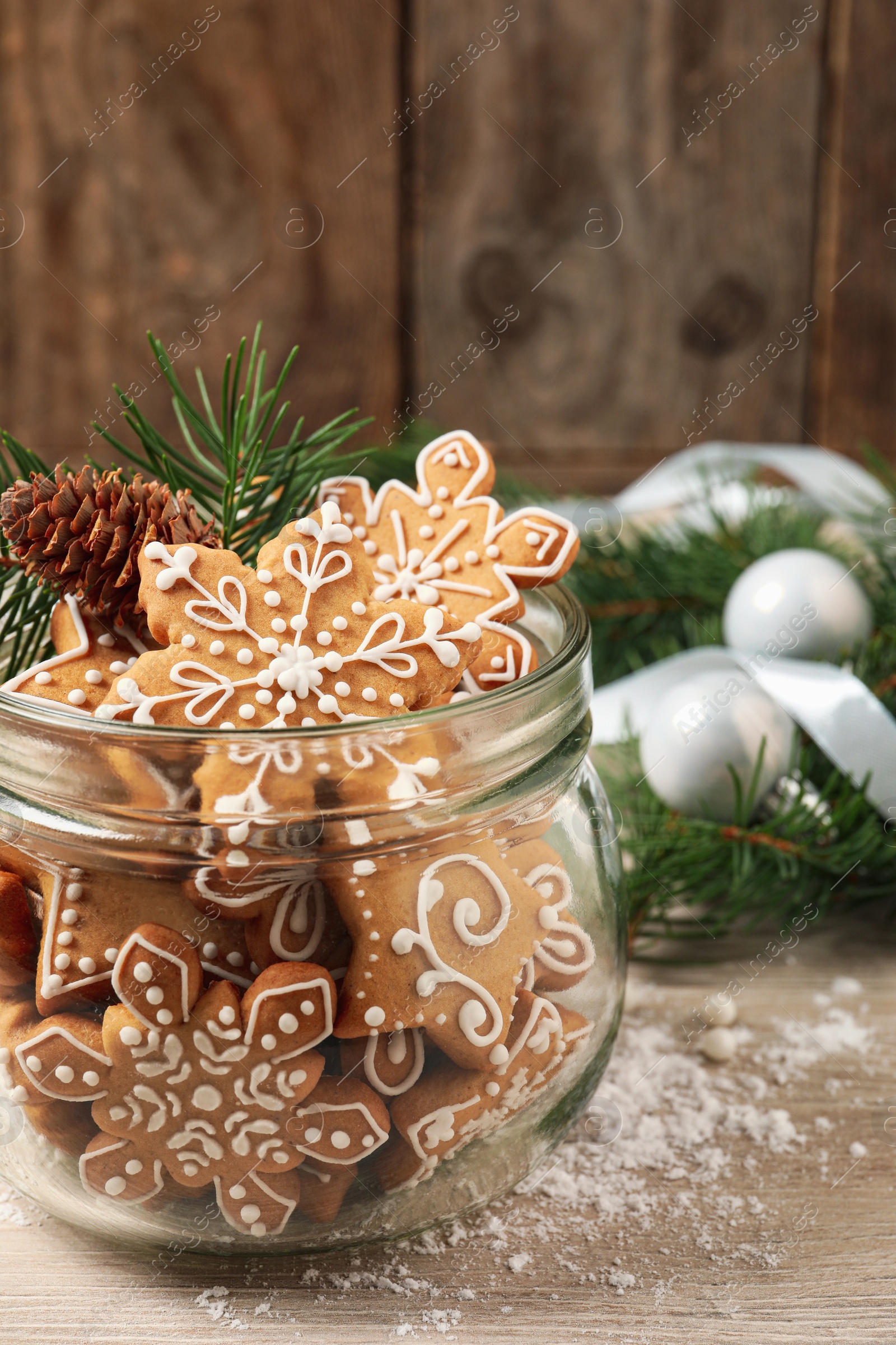 Photo of Tasty Christmas cookies in glass jar and festive decor on beige wooden table