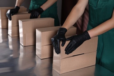 Photo of People packing cardboard boxes at production line, closeup