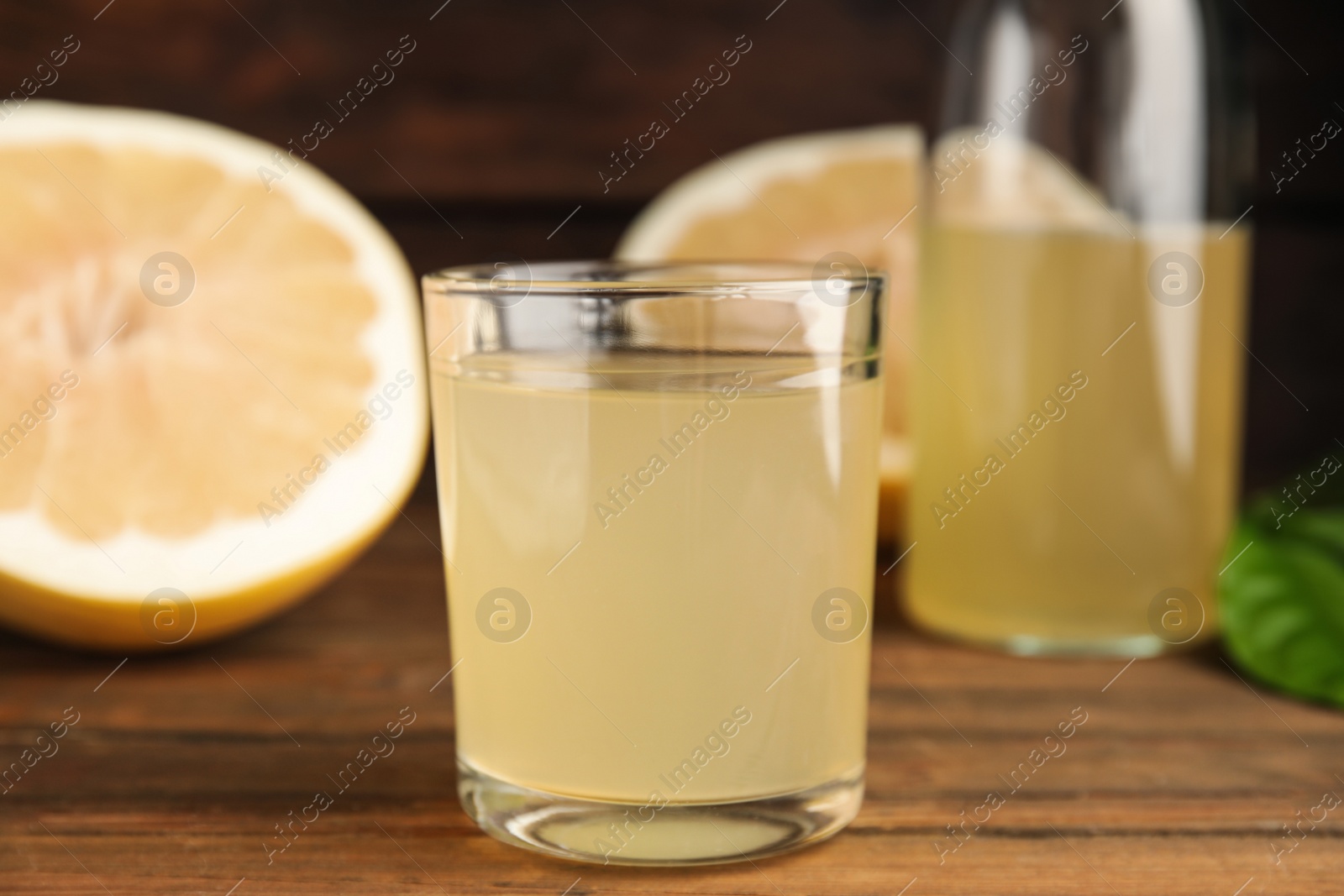 Photo of Glass of fresh pomelo juice on wooden table, closeup