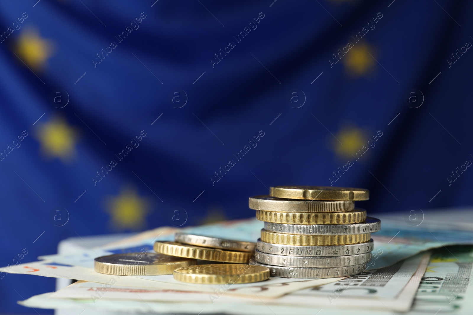 Photo of Coins and banknotes on table against European Union flag, space for text