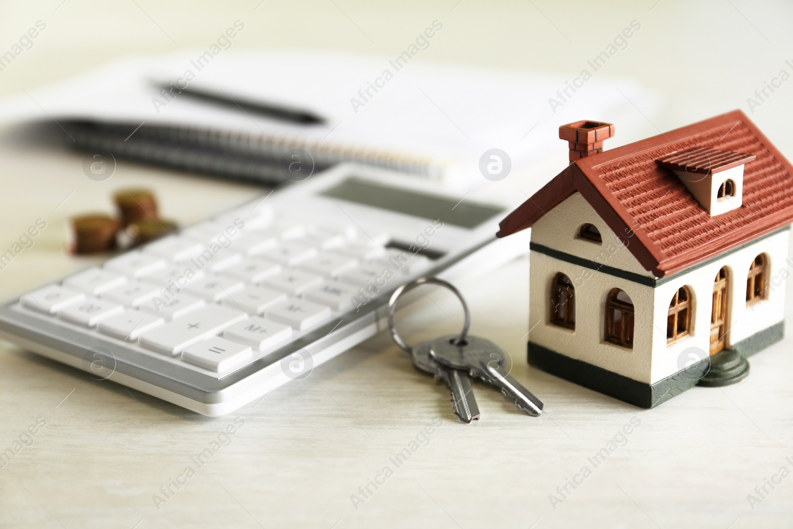 Photo of Calculator, house model, keys and documents on light table. Real estate agent's workplace