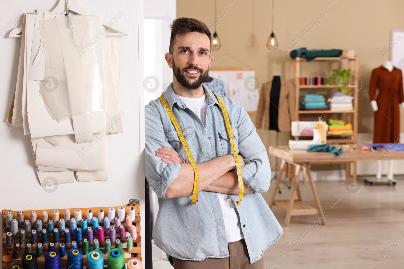 Photo of Happy dressmaker with measuring tape in workshop