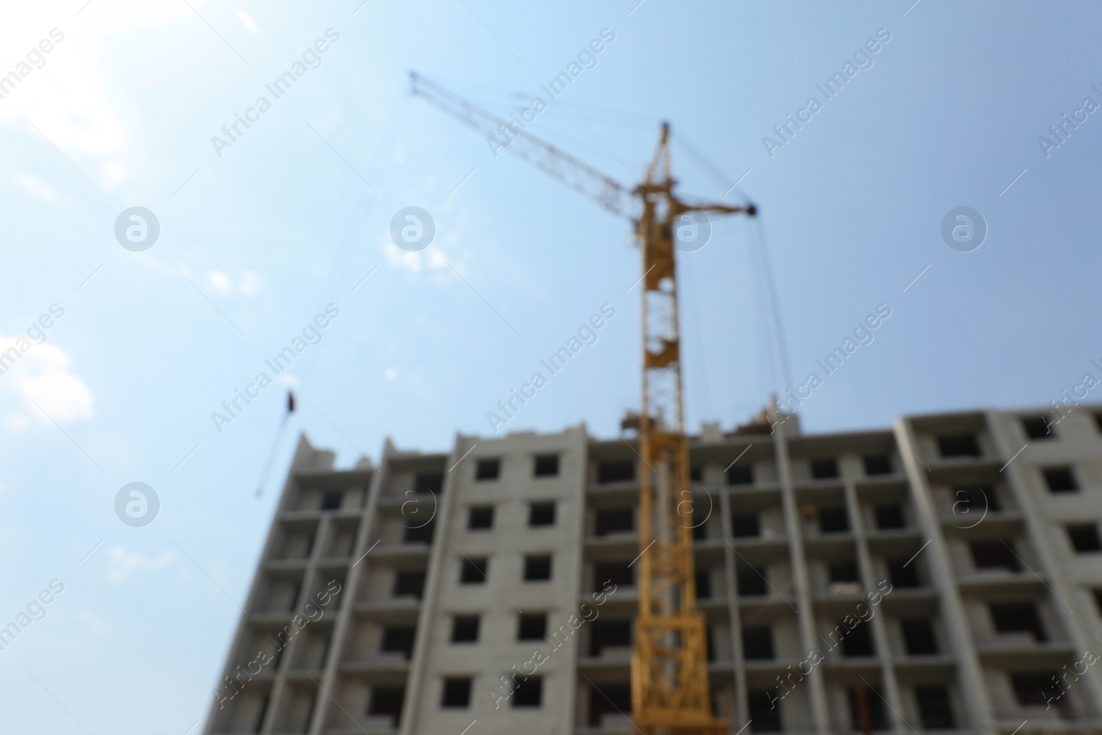 Photo of Blurred view of unfinished building and construction crane outdoors