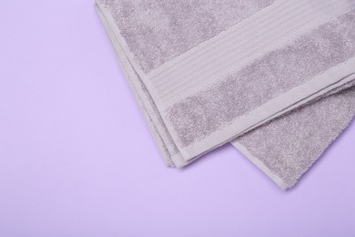 Photo of Terry towel on violet background, top view. Space for text