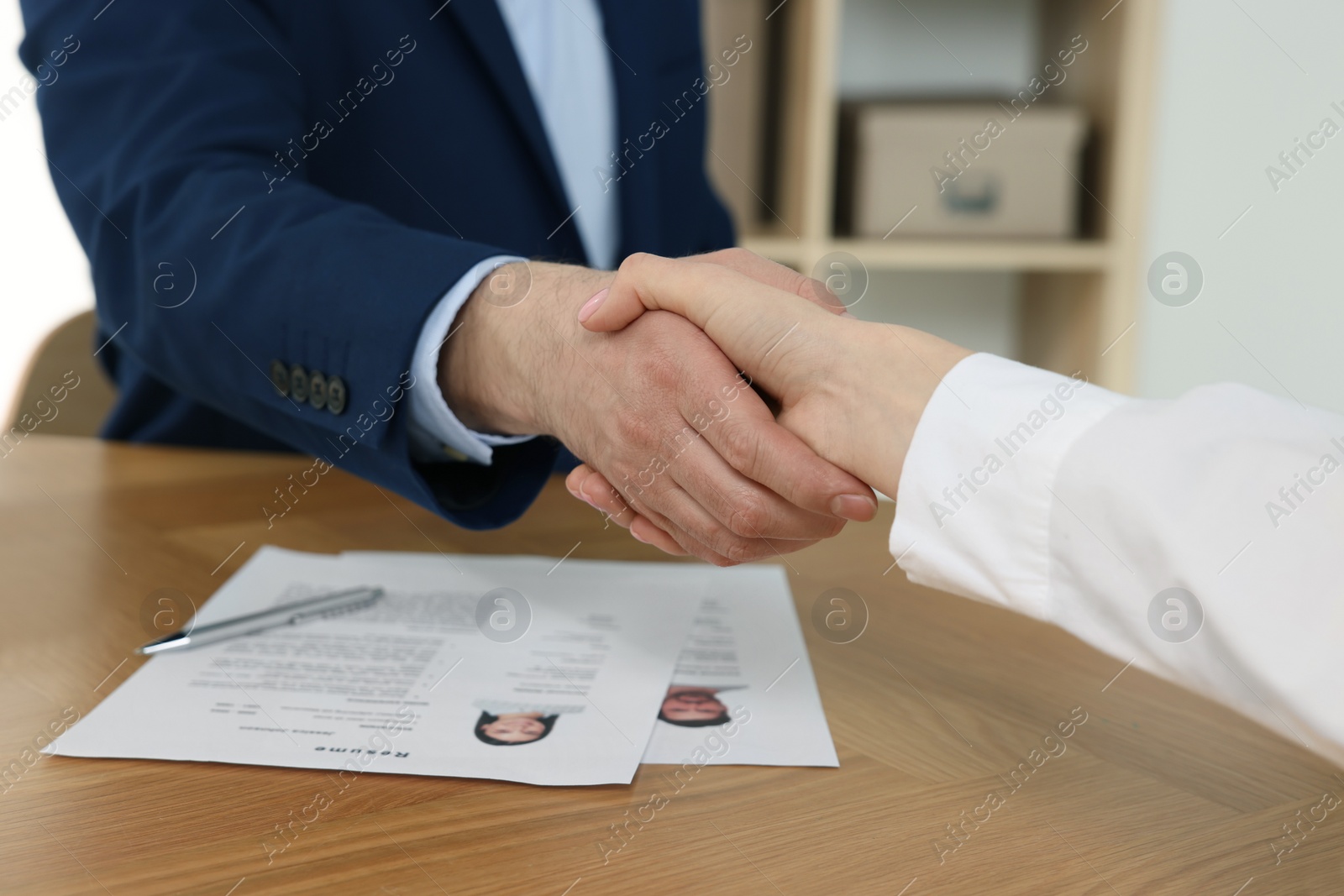 Photo of Human resources manager shaking hands with applicant during job interview in office, closeup