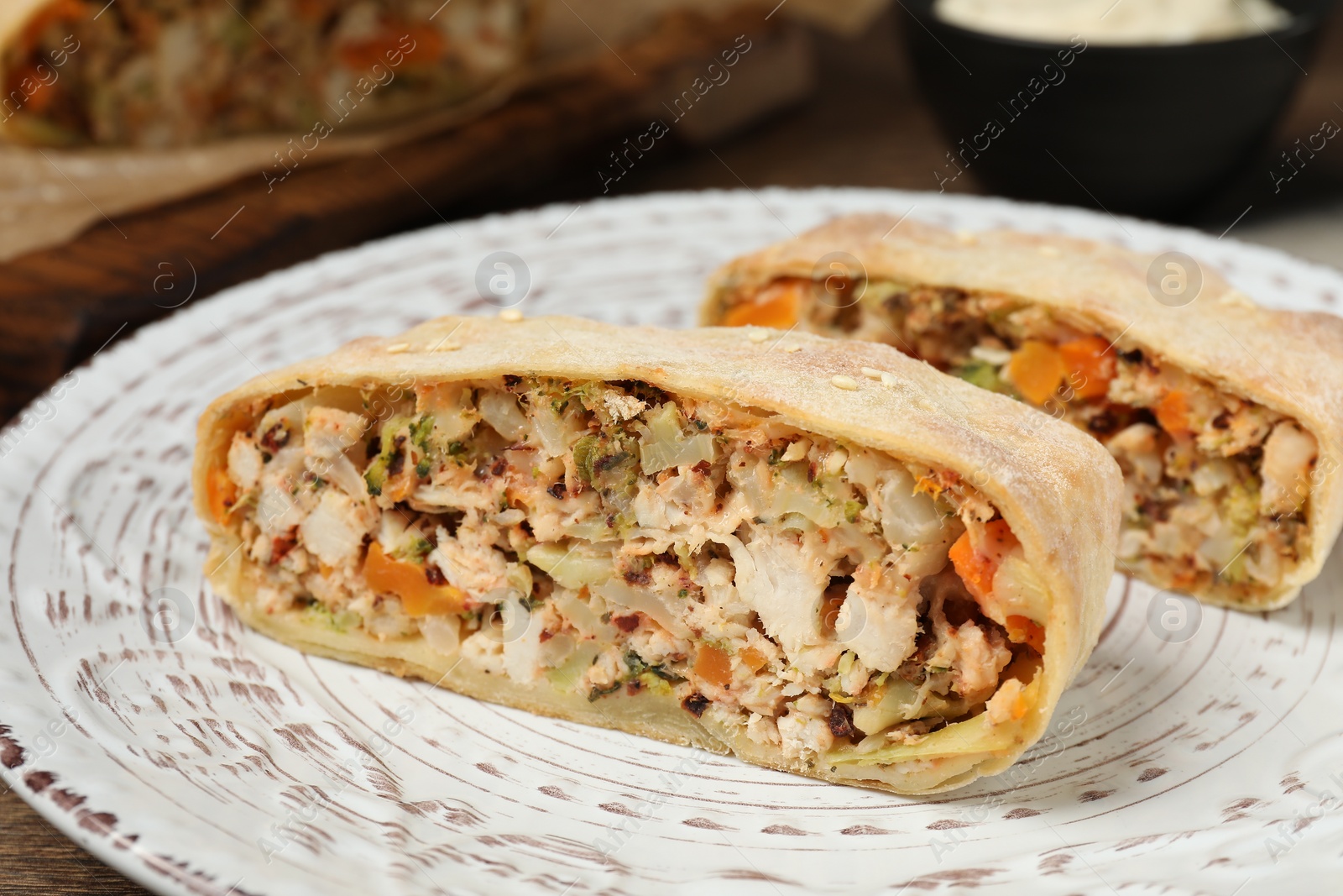 Photo of Pieces of delicious strudel with chicken and vegetables on table, closeup