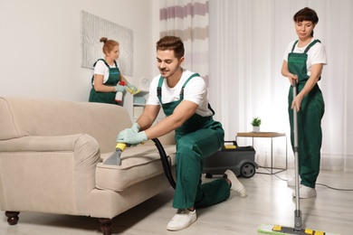 Photo of Team of professional janitors working in living room. Cleaning service
