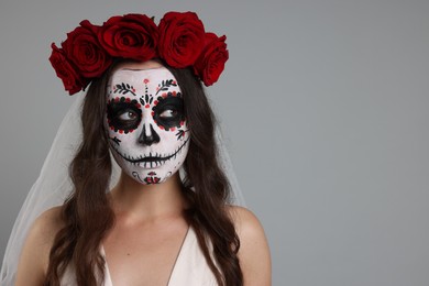 Young woman in scary bride costume with sugar skull makeup and flower crown on light grey background, space for text. Halloween celebration