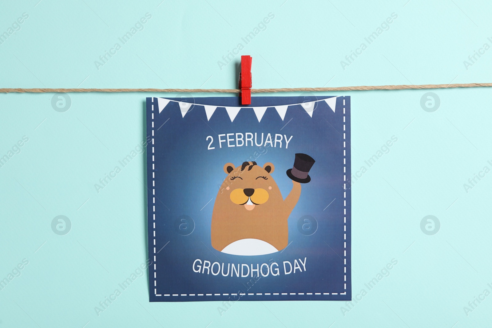 Photo of Happy Groundhog Day greeting card hanging on turquoise background