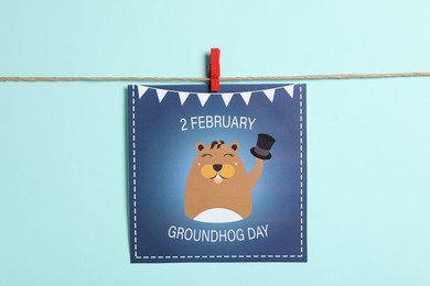 Happy Groundhog Day greeting card hanging on turquoise background
