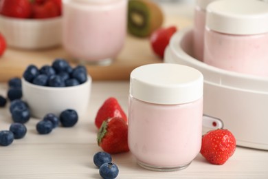 Photo of Portion jars for yogurt maker and different fruits on white wooden table, closeup