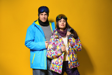 Photo of Couple wearing stylish winter sport clothes on yellow background