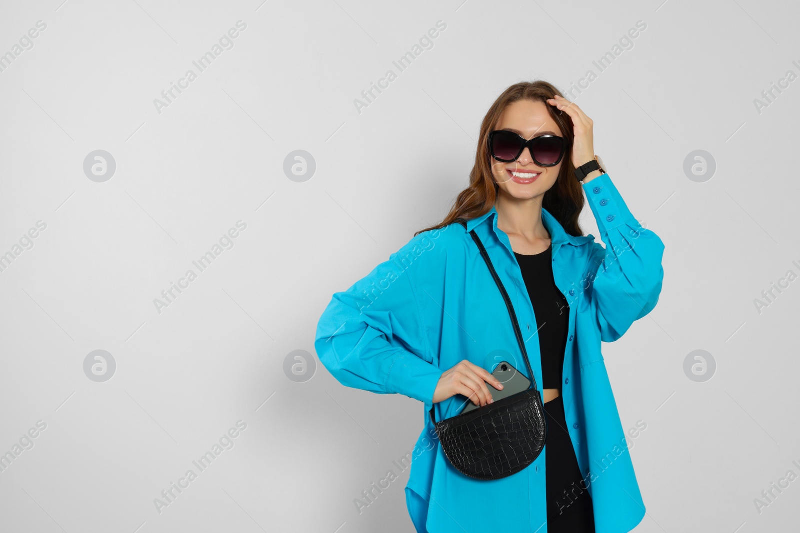 Photo of Beautiful young woman in fashionable outfit with stylish bag on white background, space for text