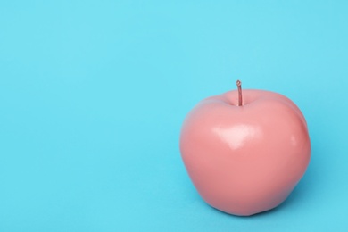 Photo of Coral painted apple on light blue background. Space for text