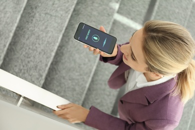 Photo of Young woman using voice search on smartphone indoors, above view