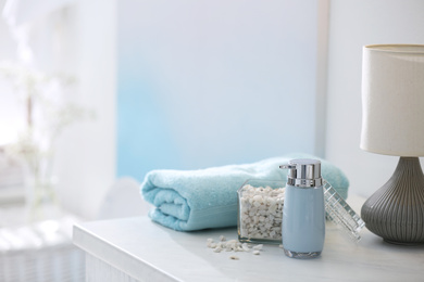 Photo of Soap dispenser, sea salt and towel on bathroom counter