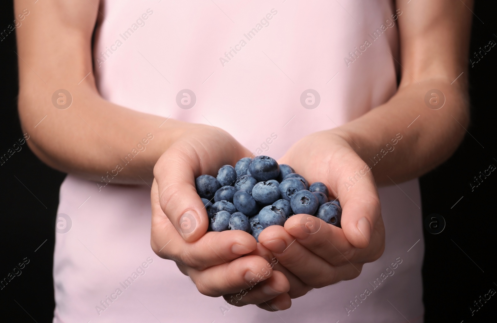 Photo of Woman holding juicy fresh blueberries, closeup view