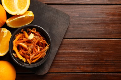 Bowl with dry orange peels and fresh fruits on wooden table. Space for text