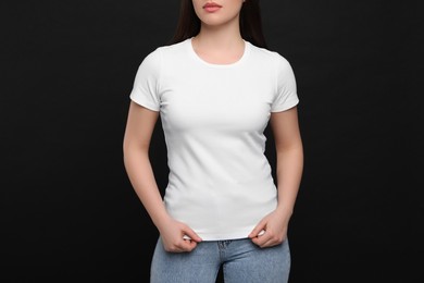 Woman wearing white t-shirt on black background, closeup
