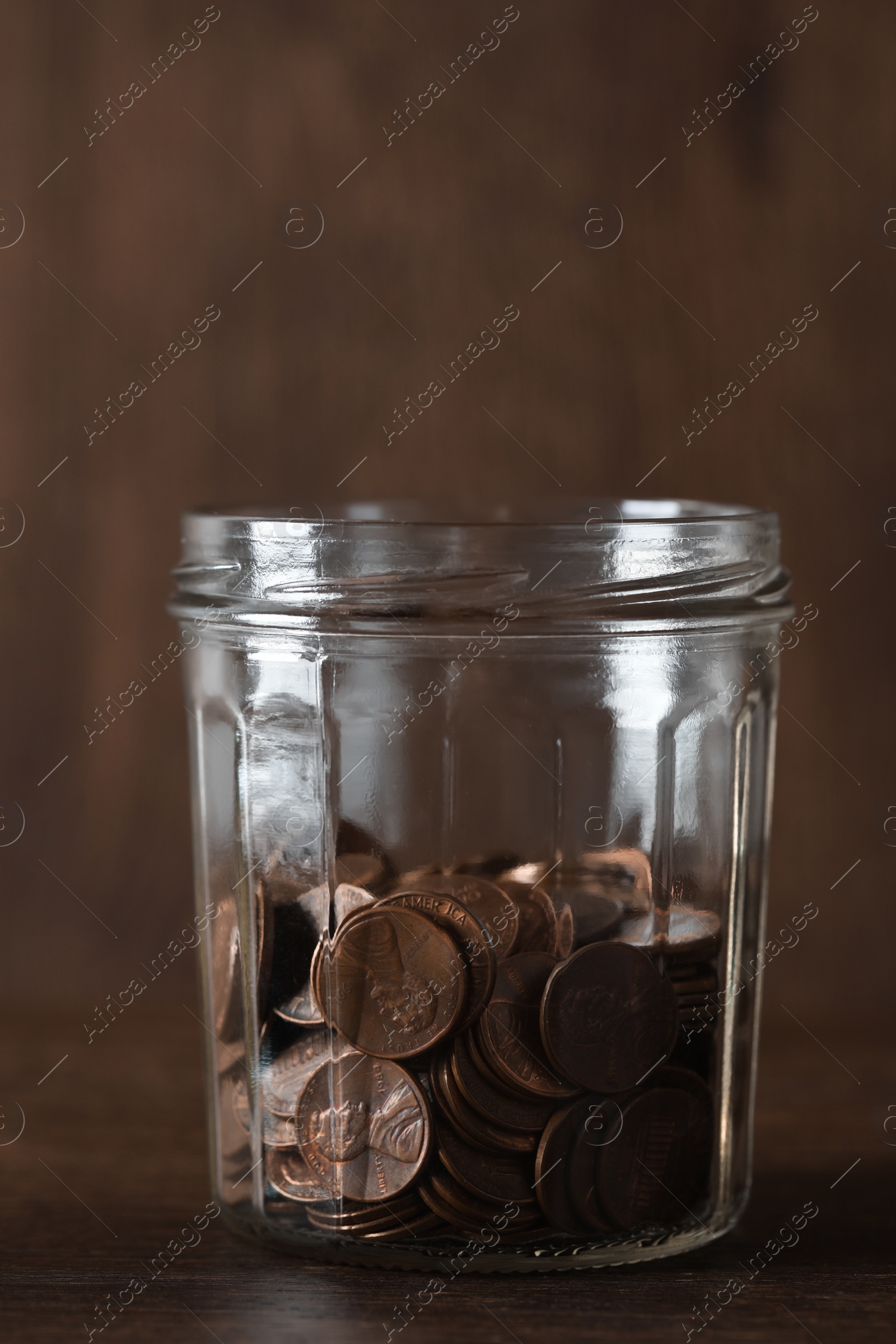 Photo of Glass jar with coins on wooden table, closeup