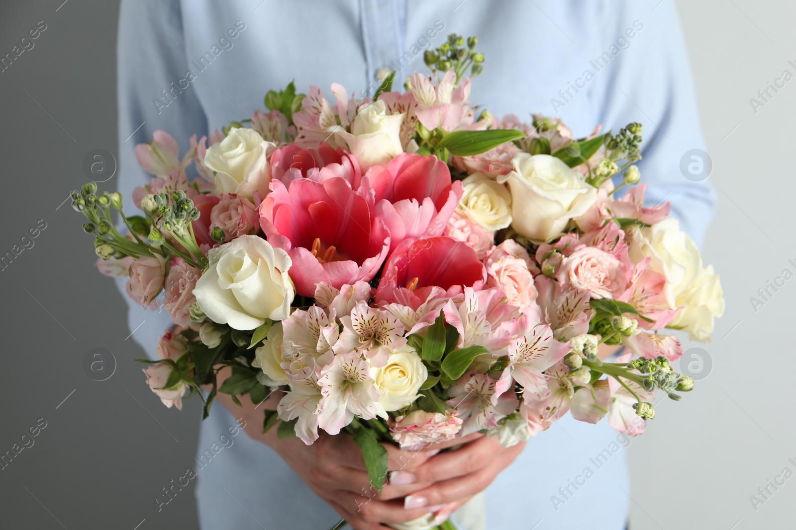 Photo of Woman with beautiful bouquet of fresh flowers on light background, closeup