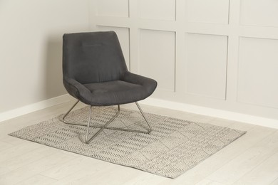 Photo of Stylish grey armchair near light wall in room. Space for text