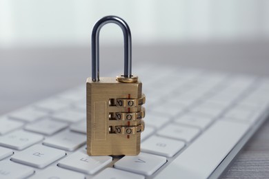 Photo of Metal code padlock and computer keyboard on table, closeup. Cyber security concept