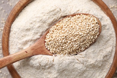 Photo of Wooden spoon with seeds on quinoa flour in bowl, top view