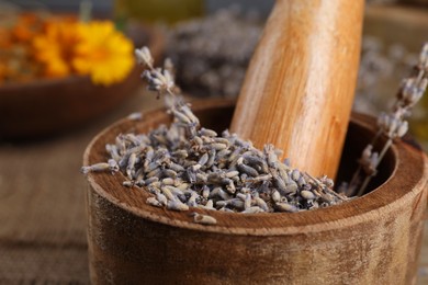 Photo of Mortar with pestle and dry lavender flowers on table, closeup. Medicinal herbs