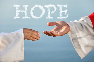 Concept of hope. Man reaching for Jesus Christ's hand near water outdoors, closeup