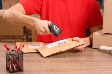 Photo of Post office worker with scanner reading parcel barcode at counter, closeup