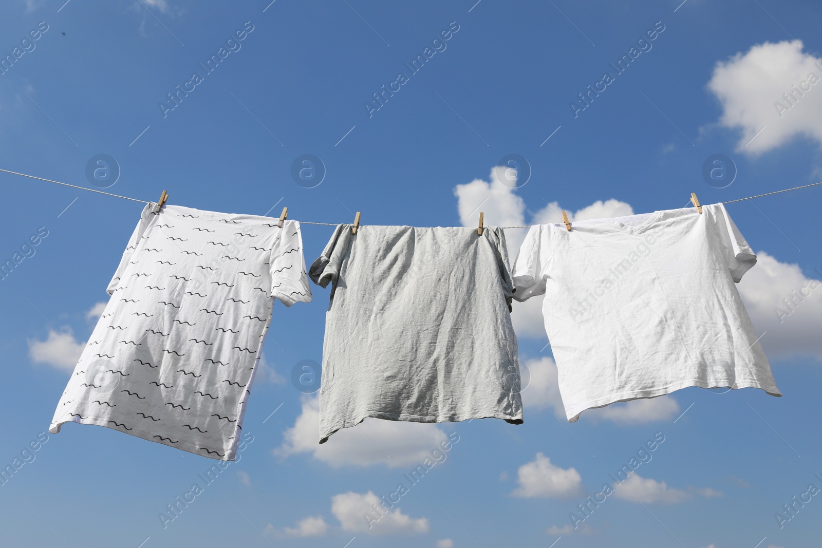 Photo of Washing line with clean clothes against sky. Drying laundry outside