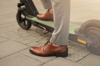 Photo of Businessman with modern kick scooter on city street, closeup