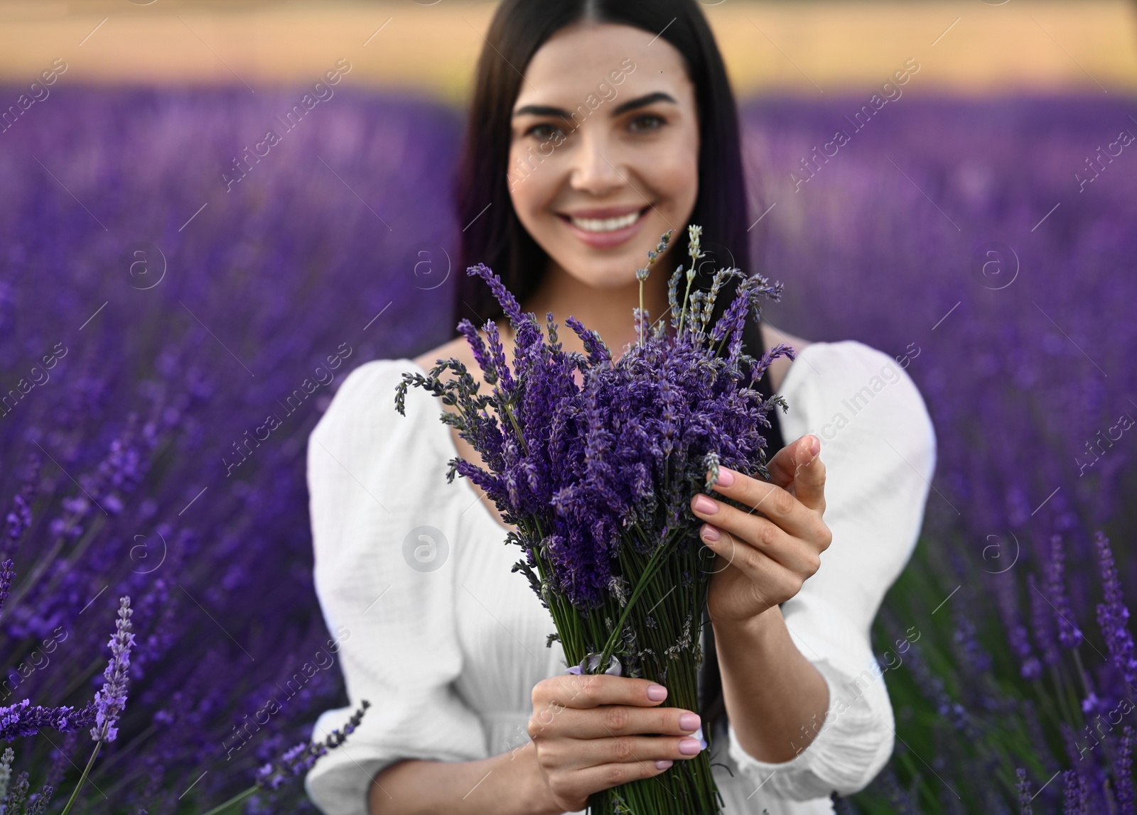 Photo of Beautiful young woman with bouquet in lavender field