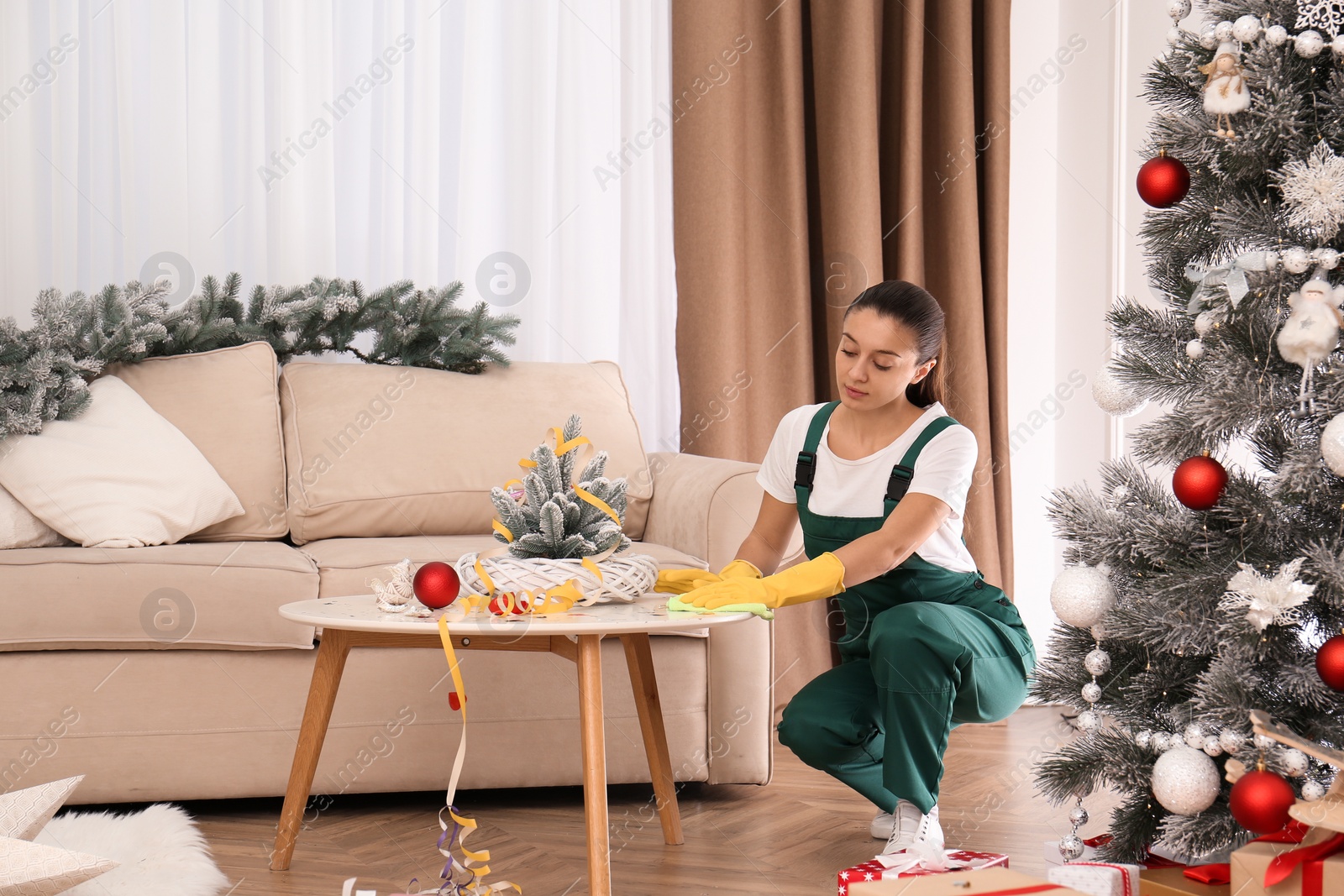 Photo of Woman from cleaning service working in messy room after New Year party