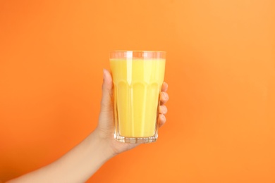 Woman holding glass with delicious smoothie on color background