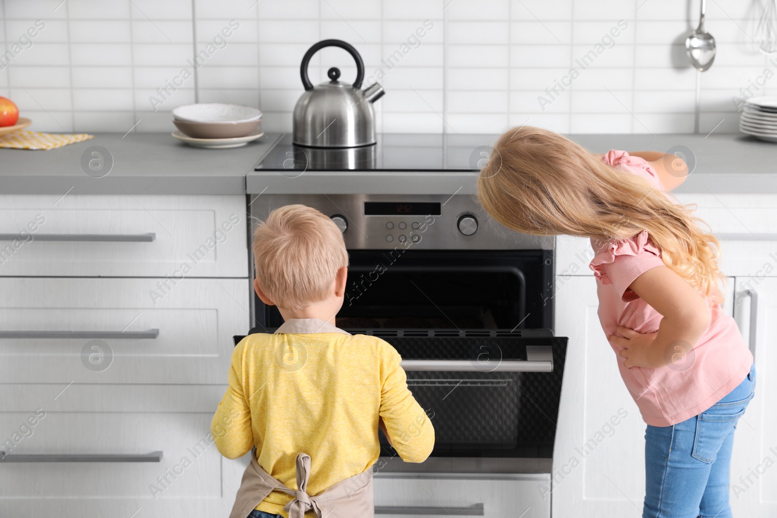 Photo of Little kids baking something in oven at home