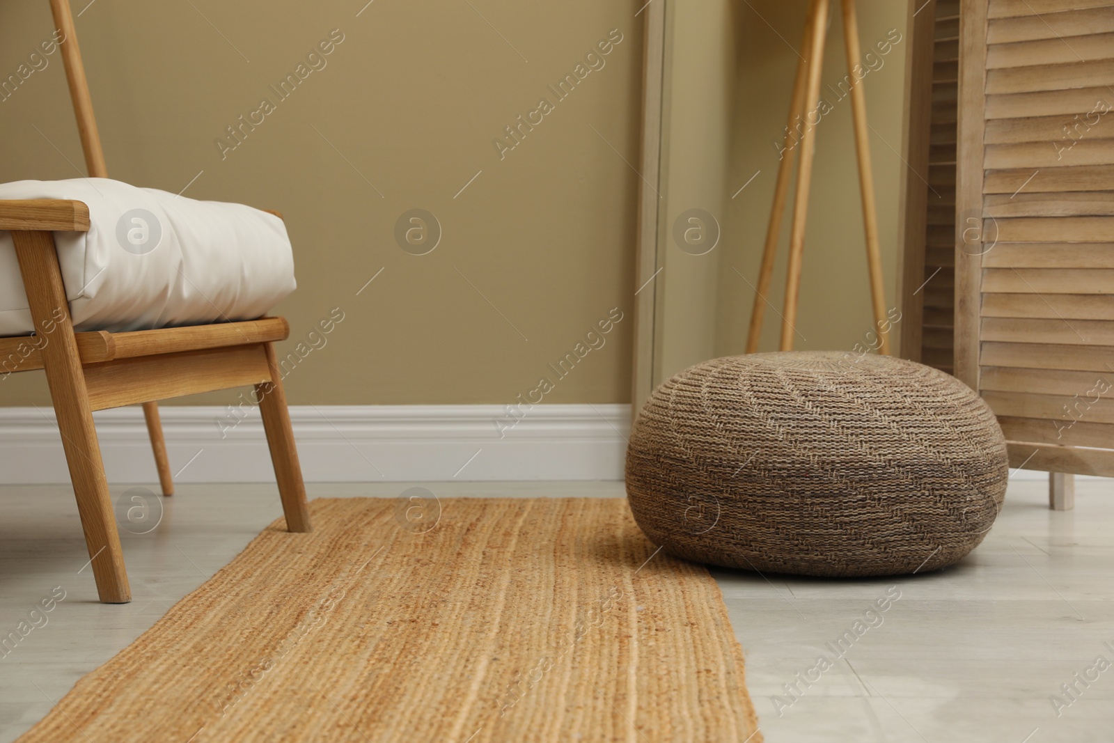 Photo of Stylish knitted pouf and armchair in room
