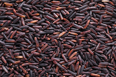 Photo of Uncooked organic brown rice as background, top view