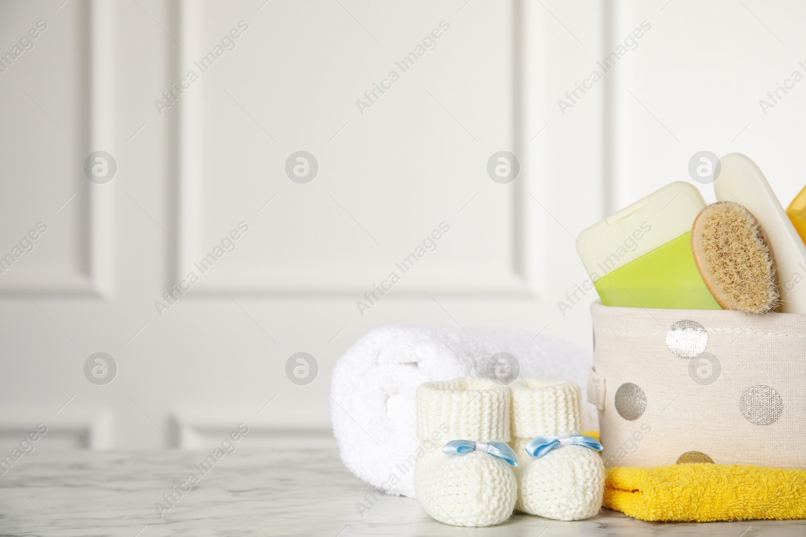 Photo of Baby booties and accessories on white marble table indoors. Space for text