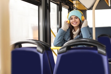 Photo of Young woman listening to music with headphones in public transport