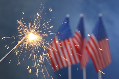 Photo of Burning sparkler against USA flags, closeup with space for text. Happy Independence Day