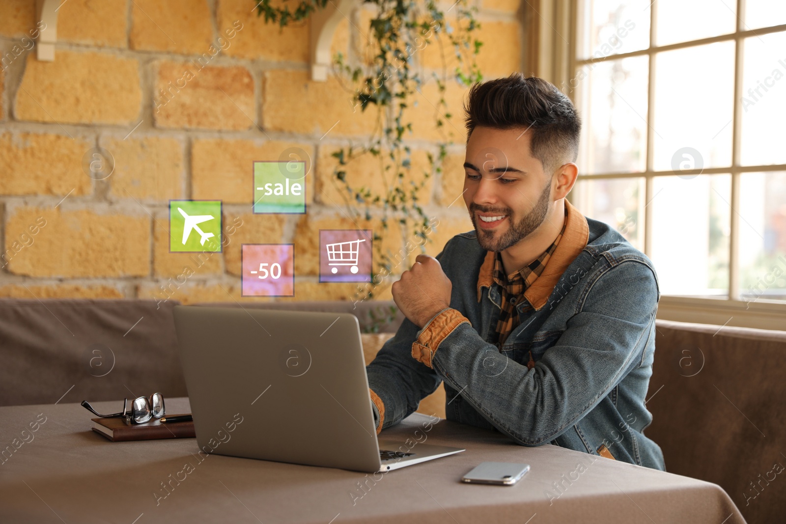 Image of Young man using laptop at table in cafe. Online shopping