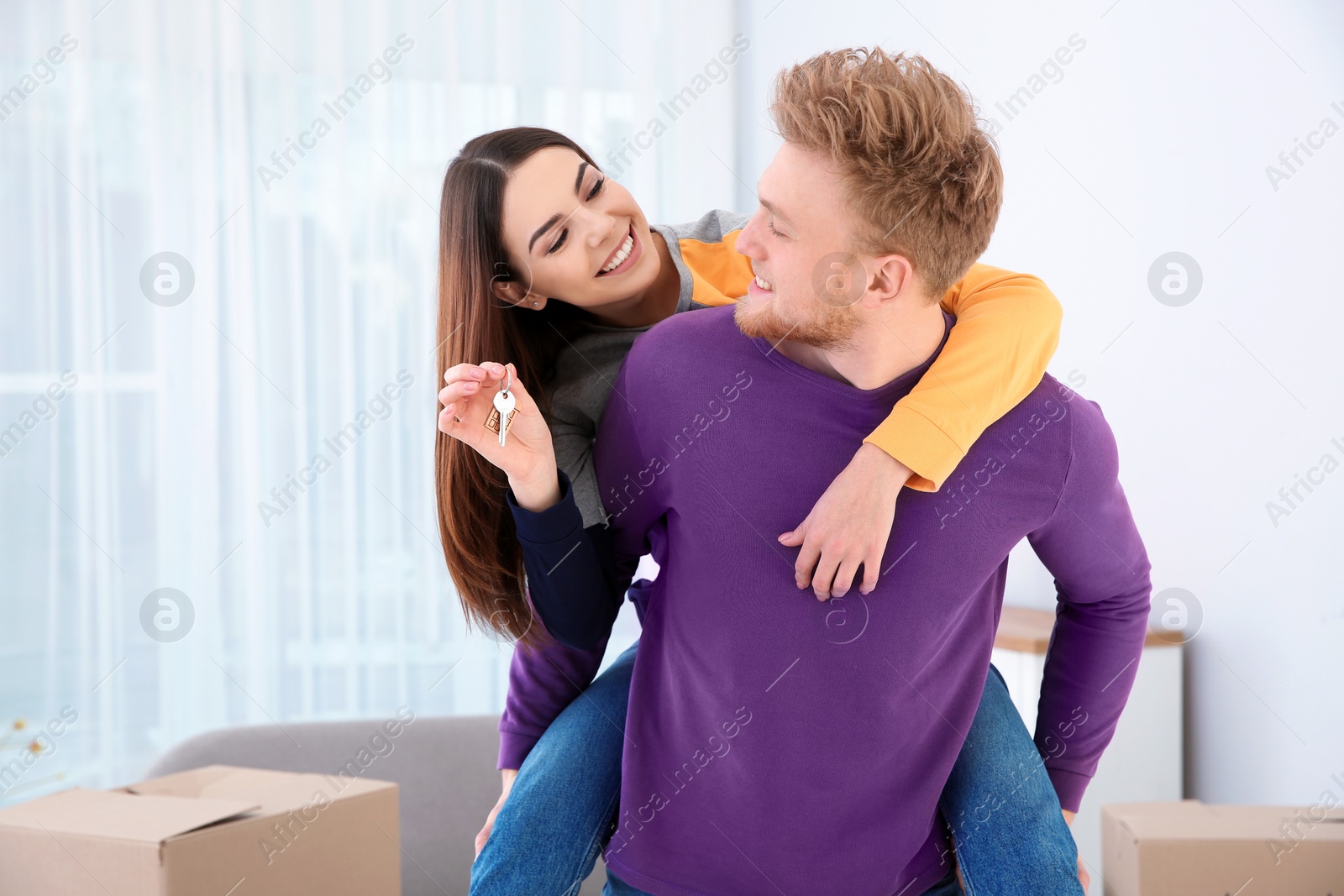 Photo of Young couple with key from their new house indoors. Moving day