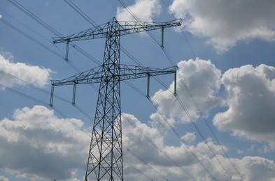 Modern high voltage tower against blue sky, low angle view