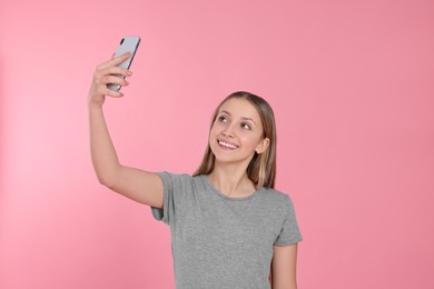 Photo of Teenage girl taking selfie on pink background