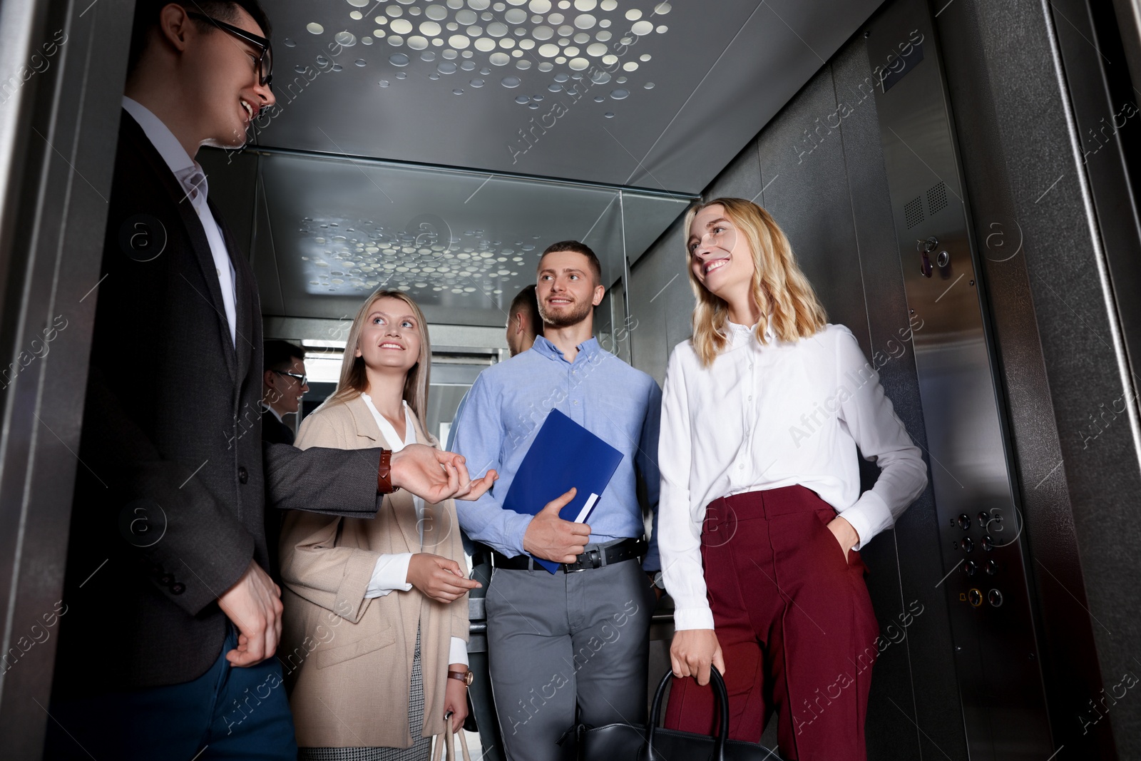 Photo of Group of office workers talking in modern elevator